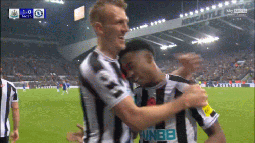 Soccer Players Hugging in Front of Newcastle Sign