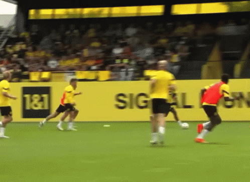 Soccer Players on Field With T & T Sign