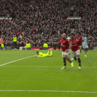 Soccer Players Running on Field in Front of Crowd
