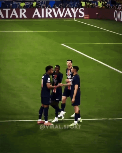 soccer players shaking hands on a field with an advertisement for qatar airways in the background