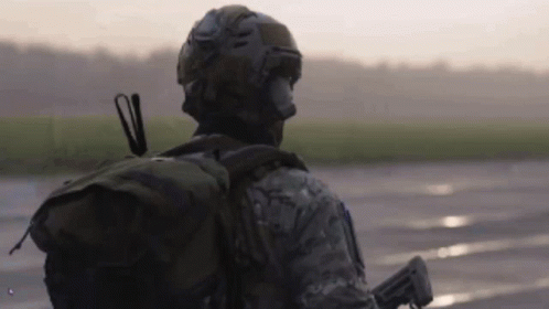 Soldier Walking on Wet Road With Backpack Gun