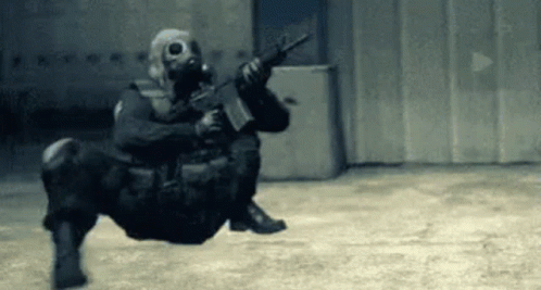 Soldier Wearing Gas Mask Holding Gun Sitting on Floor