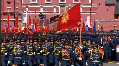 Soldiers Marching in Front of Building with Portrait