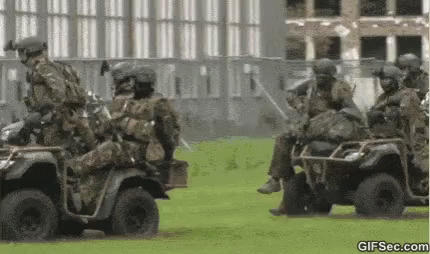 Soldiers Riding ATVs on Grassy Field