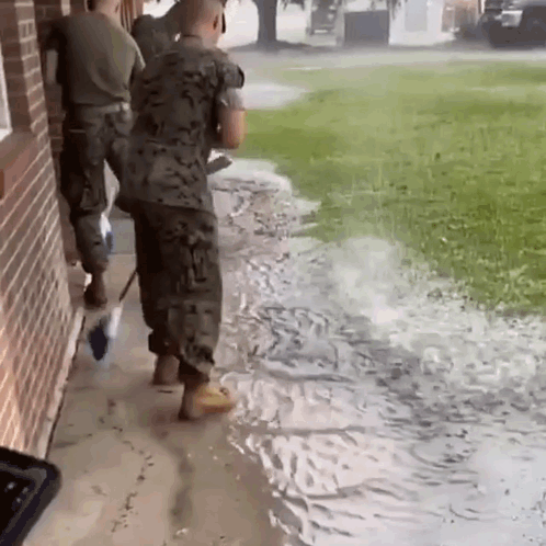 Soldiers Standing on Sidewalk in Flooded Area