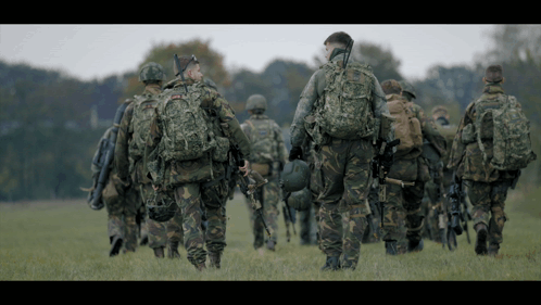 Soldiers Walking in Field, One with Helmet