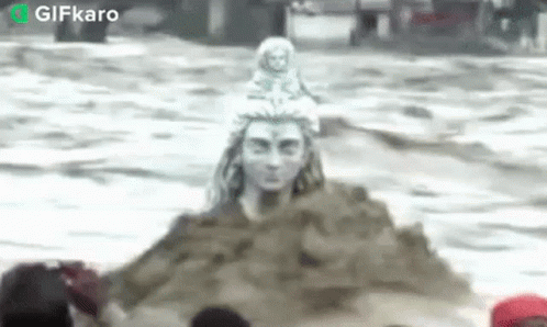 Statue of Man Sitting on Sand Pile in Ocean