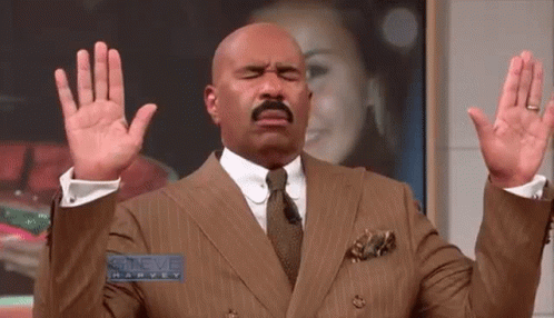 Steve Harvey In Suit And Tie With Hands Up GIF
