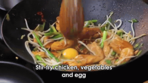 stir fry chicken vegetables and egg in a wok with a wooden spoon