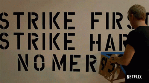 Strike First Strike Hard No Mercy Stenciled On Wall GIF
