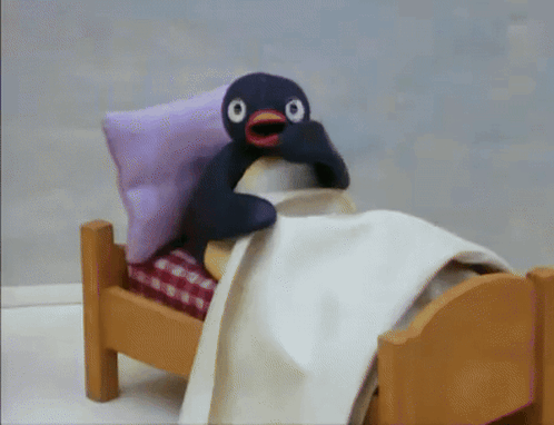 Stuffed Penguin Lying in Bed