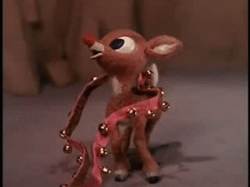 Stuffed Reindeer With Red Nose In Front Of Christmas Tree GIF