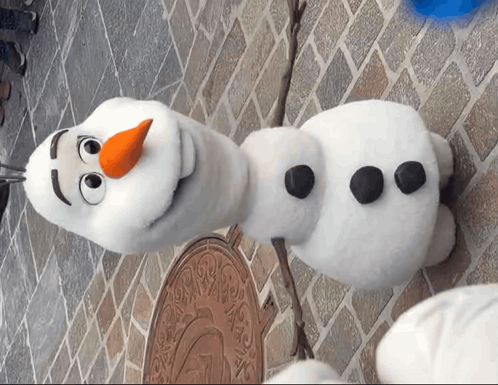Stuffed Snowman With Orange Nose on Brick Wall