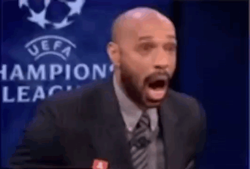 Suited Man Speaking Into Microphone with Champions League Logo