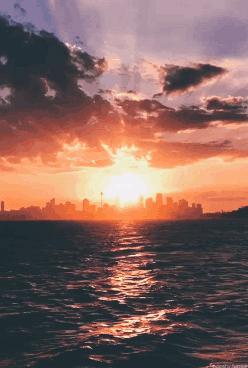Sunset Over Ocean With Distant City