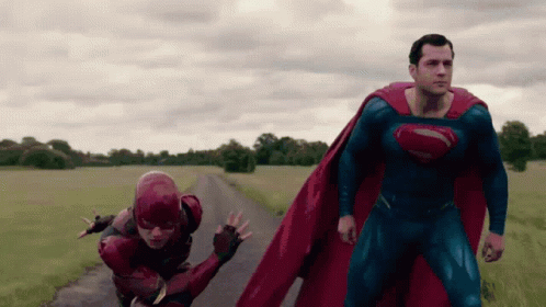 Superman And The Flash Are Running Down A Road In A Field GIF