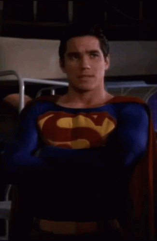 Superman Costume Man Standing With Arms Crossed in Dark Room