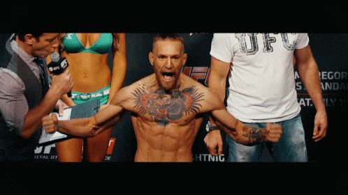 Tattooed Man Standing in Front of Bikini Woman and UFC Shirt Man
