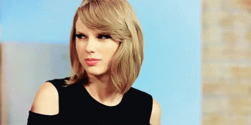 Taylor Swift in Black Off-Shoulder Top Looking at Camera