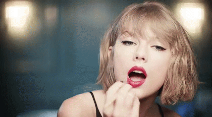 Taylor Swift Is Wearing Red Lipstick And Applying It To Her Lips . GIF