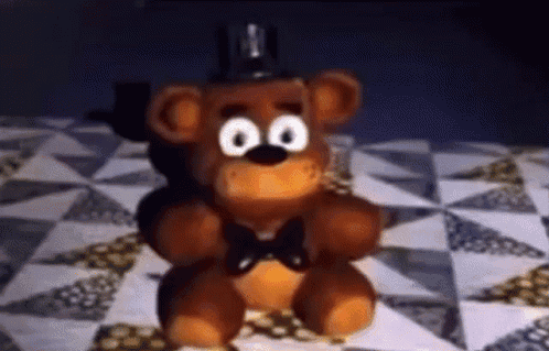 Teddy Bear Sitting On Quilt On Bed GIF