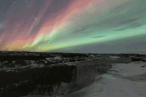 The Aurora Borealis Is Shining Over A Waterfall GIF