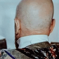 the back of a bald man 's head with a floral jacket on