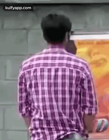 The Back Of A Man In A Plaid Shirt Is Shown . GIF
