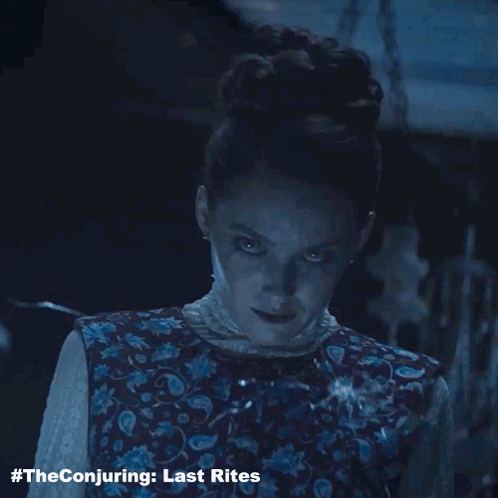The Conjuring Last Rites Poster With A Woman In A Floral Vest GIF