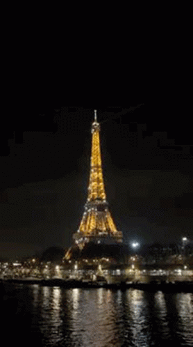 the eiffel tower is lit up at night in paris , france .