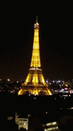 The Eiffel Tower Is Lit Up At Night With A Light Coming Out Of The Top GIF