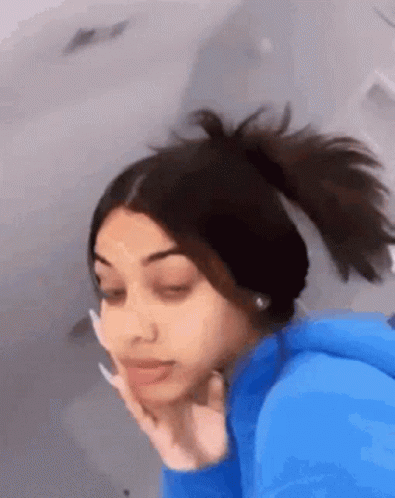 The Girl Is Wearing A Blue Hoodie And A Ponytail . GIF