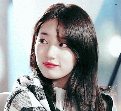 The Girl Is Wearing A Plaid Scarf Around Her Neck And Looking At The Camera . GIF