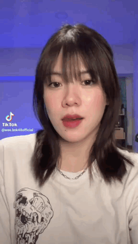 The Girl Is Wearing A White T-Shirt With A Skull On It And A Necklace . GIF