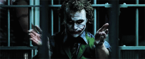 The Joker Is Behind Bars In A Dark Room GIF