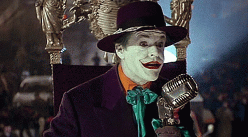 The Joker Is Sitting On A Throne Holding A Microphone In His Hand . GIF