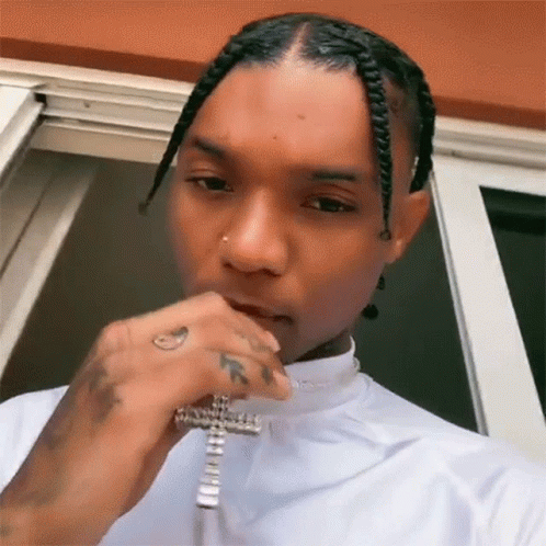 The Man Is Wearing A White Shirt And A Cross Necklace . GIF