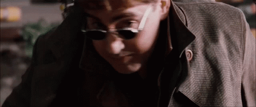 the man is wearing sunglasses and a trench coat .