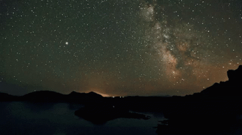 The Milky Way Is Visible In The Night Sky Over A Lake GIF
