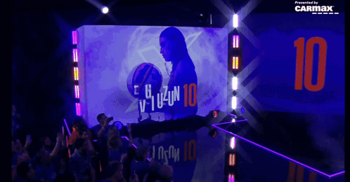 The Number 10 Is Projected On A Wall Behind A Crowd Of People GIF