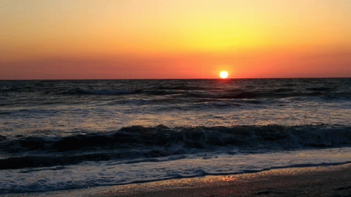 The Sun Is Setting Over The Ocean And The Waves Are Breaking On The Beach GIF
