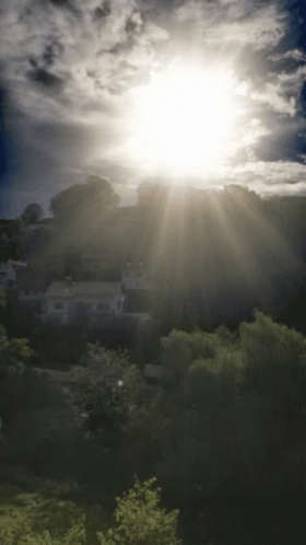 The Sun Is Shining Brightly Through The Clouds Over A Residential Area GIF