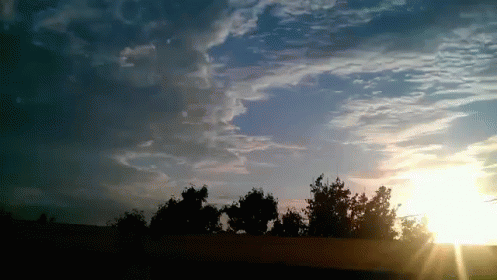 The Sun Is Shining Through The Clouds Over A Fence GIF