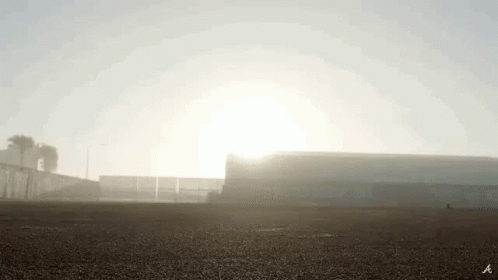 The Sun Is Shining Through The Fog Over A Stadium . GIF