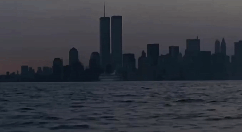 The Twin Towers Are Visible In The Distance Behind A Boat GIF