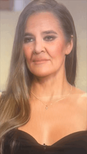 The Woman Is Wearing A Black Dress And A Necklace . GIF