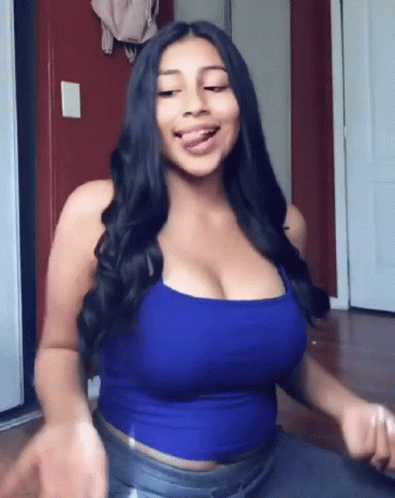The Woman Is Wearing A Blue Tank Top And Jeans And Has A Large Breast . GIF