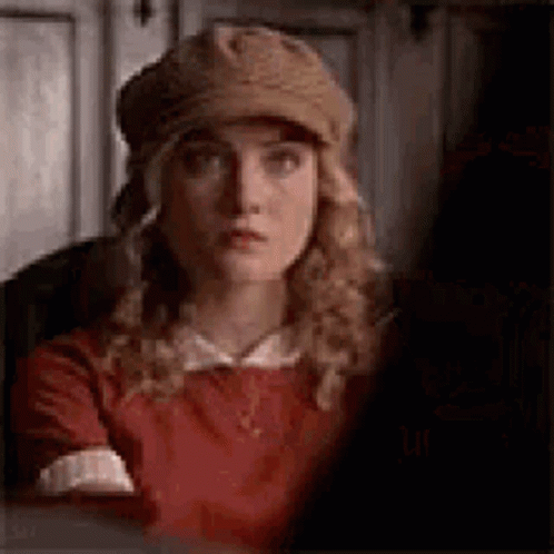 The Woman Is Wearing A Hat And A Red Dress . GIF