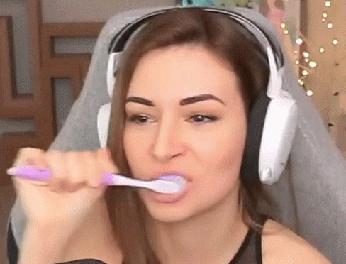 The Woman Is Wearing Headphones And Brushing Her Teeth With A Purple Toothbrush . GIF