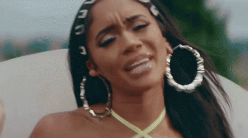 The Woman Is Wearing Hoop Earrings And A Yellow Necklace . GIF